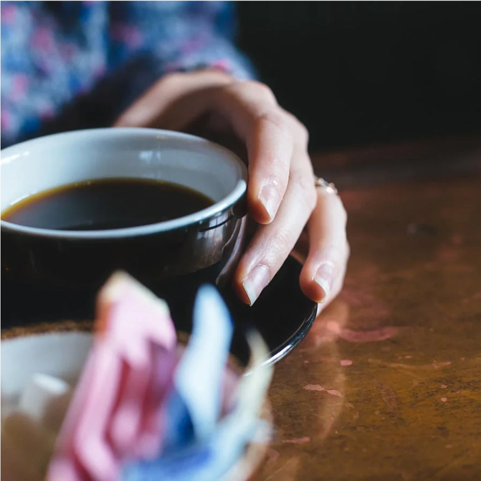 Hand holding a cup of coffee on a table