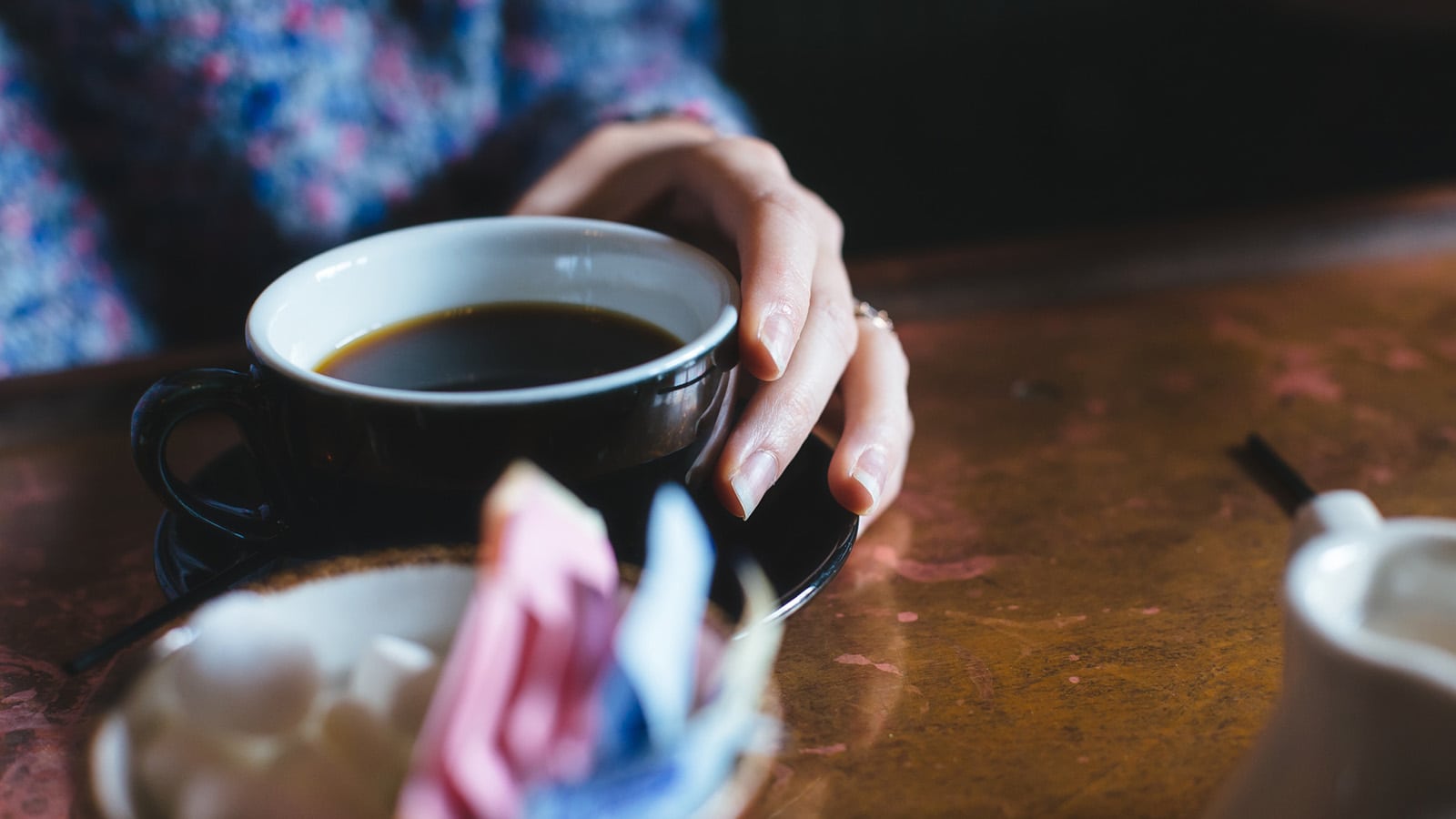 Woman's hand holding a cup of black coffee