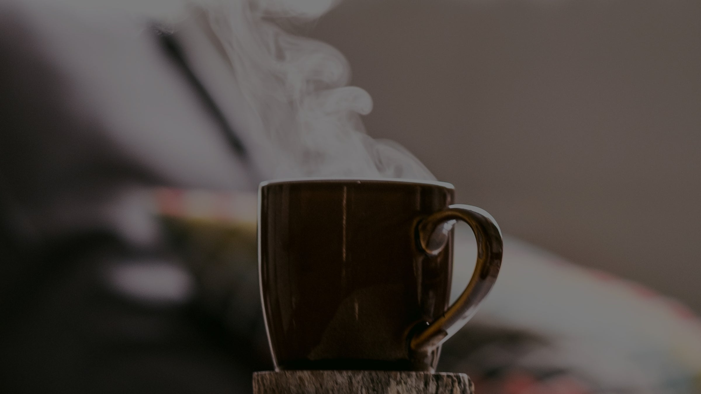 Steaming cup of coffee on a wooden coaster